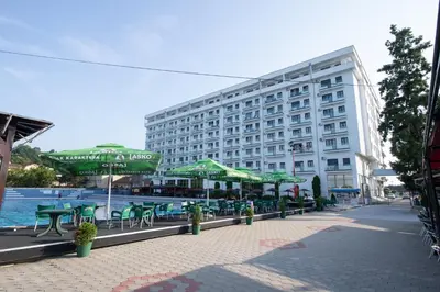 a large building with green tables and chairs in front of it at Petković apartmani 48 in Jagodina