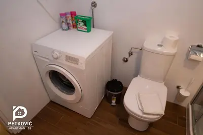 a bathroom with a washing machine and a toilet at Petković apartmani 34 in Jagodina