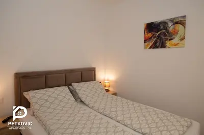 a bed in a bedroom with a picture on the wall at Petković apartmani 34 in Jagodina