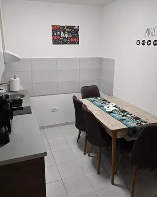 a kitchen with a table with chairs and a sign on the wall at Apartman Muzika Jagodina in Jagodina