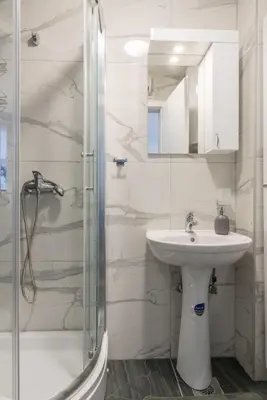 a white bathroom with a sink and a shower at Apartman Ina in Vrnjačka Banja