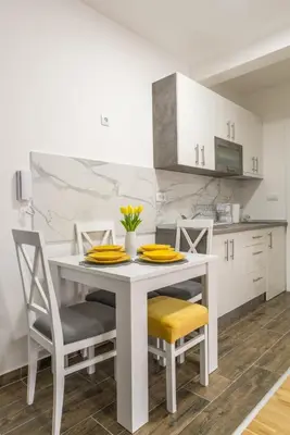 a white kitchen with a white table and chairs at Apartman Ina in Vrnjačka Banja