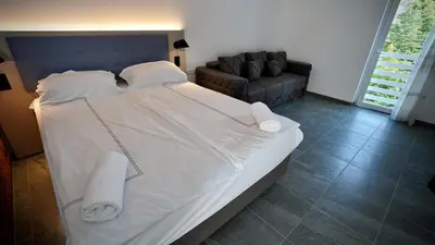a large white bed in a room with a couch at Apartmani Vila Katarina in Vrnjačka Banja
