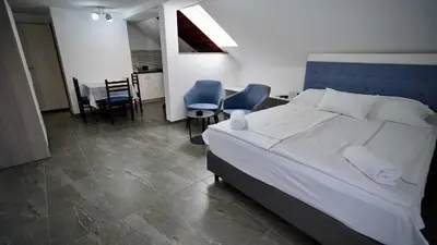 a bedroom with a bed and two chairs and a table at Apartmani Vila Katarina in Vrnjačka Banja