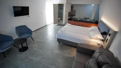 a bedroom with a bed and two chairs and a couch at Apartmani Vila Katarina in Vrnjačka Banja