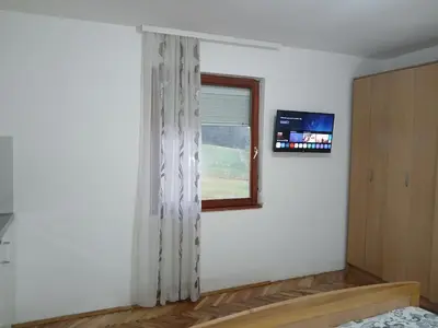 a bedroom with a window and a tv on the wall at Green apartments 2 in Kuršumlija
