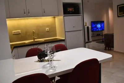 a kitchen with a white table and red chairs at Lux Apartman Crnjanski II, Jagodina in Jagodina
