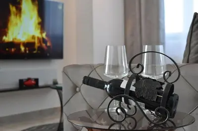 two wine glasses on a glass table in front of a fire at Lux Apartman Crnjanski II, Jagodina in Jagodina