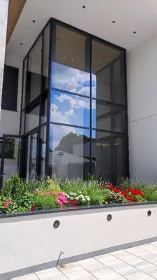 a large glass building with flowers in a window at Lux Apartman Crnjanski II, Jagodina in Jagodina