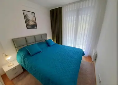 a bedroom with a large blue bed with a window at Apartman SANA & Free GARAŽA in Vrnjačka Banja