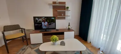 a living room with a television on a table with a chair at Apartman SANA & Free GARAŽA in Vrnjačka Banja
