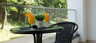 a table with two glasses of orange juice on a balcony at Apartman SANA & Free GARAŽA in Vrnjačka Banja