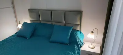 a bedroom with a bed with blue pillows and a lamp at Apartman SANA & Free GARAŽA in Vrnjačka Banja