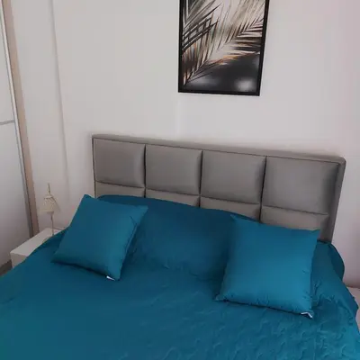 a bed with blue pillows in a bedroom at Apartman SANA & Free GARAŽA in Vrnjačka Banja
