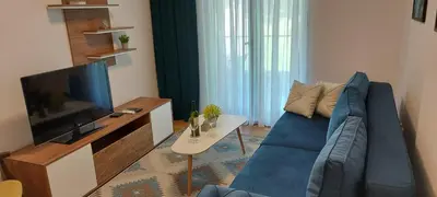 a living room with a blue couch and a tv at Apartman SANA & Free GARAŽA in Vrnjačka Banja