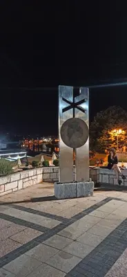 a statue of a cross with a person sitting on a wall at Lux apartment 13 center, free parking in Niš
