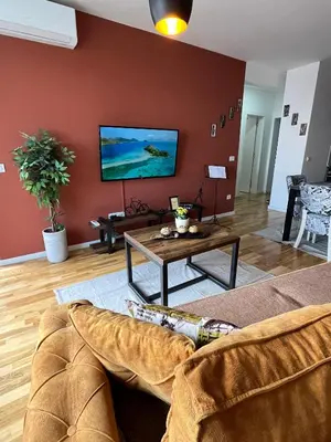 a living room with a couch and a tv on a wall at Lux apartment 13 center, free parking in Niš