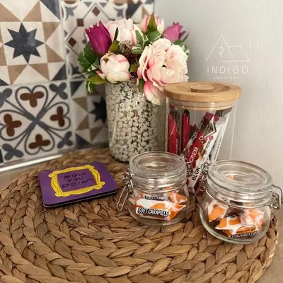 a table with two jars and a vase with flowers at Apartman Indigo in Vrnjačka Banja