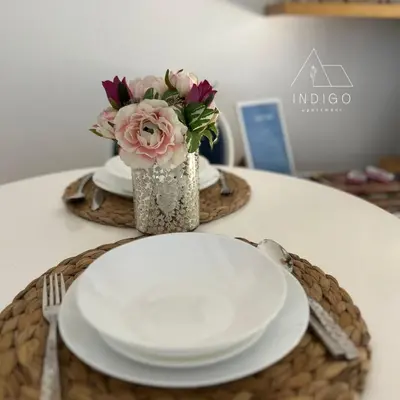 a table with a plate and a vase of flowers at Apartman Indigo in Vrnjačka Banja