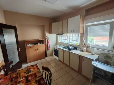 a kitchen with white cabinets and a table in it at City Park Rooms in Vranje