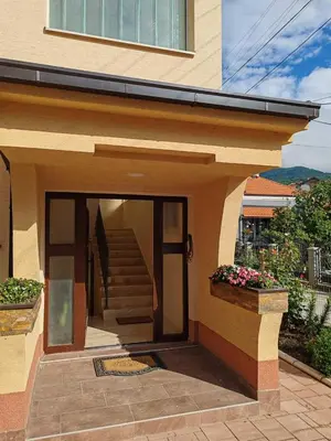 a house with a staircase and a door with flowers at City Park Rooms in Vranje