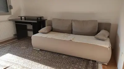 a couch sitting in a living room with a table at Stan na dan Nis in Niš