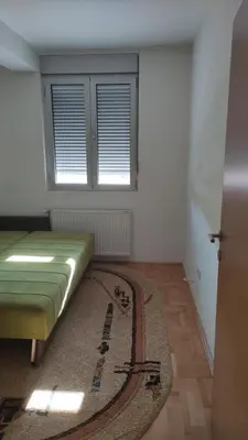 a room with a bed and a rug and a window at Stan na dan Nis in Niš