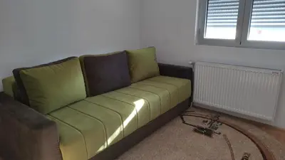 a green couch in a living room with a window at Stan na dan Nis in Niš