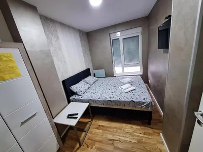 a small bedroom with a bed and a table at Lux apartment 12 center, free parking in Niš