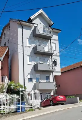 a red car parked in front of a white building at Nada-S in Soko Banja