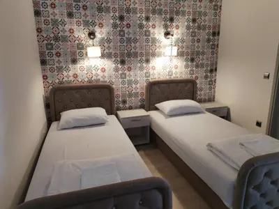 two beds in a small room with a wallpaper at UB Prenociste in Vranjska Banja