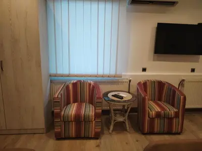 a room with two chairs and a table and a tv at UB Prenociste in Vranjska Banja
