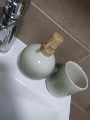 a bathroom sink with a soap dispenser and a cup at Green Apartman in Paraćin