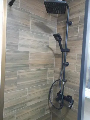 a shower in a bathroom with a wooden floor at Holiday apartament three in Niš