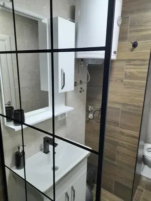 a bathroom with a glass walled shower and a toilet at Holiday apartament three in Niš