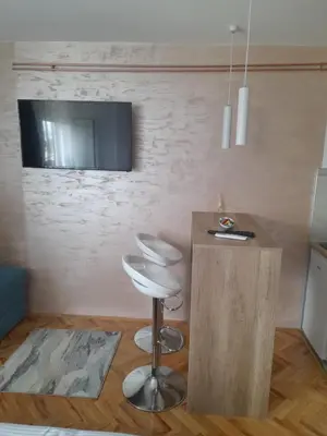 a room with a bar stool and a tv on a wall at Holiday apartament three in Niš