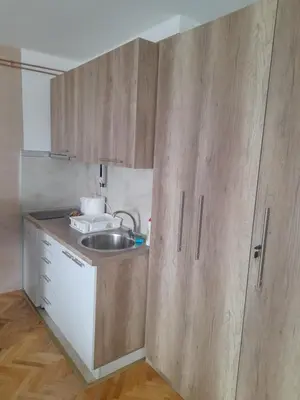 a small kitchen with a sink and wooden cabinets at Holiday apartament three in Niš