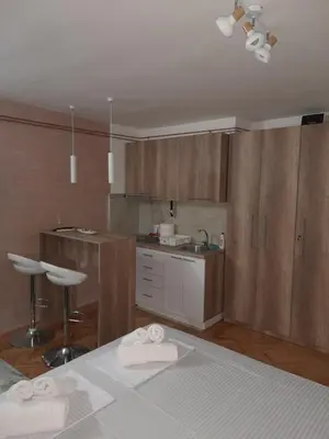 a kitchen with wooden cabinets and a sink and a bed at Holiday apartament three in Niš