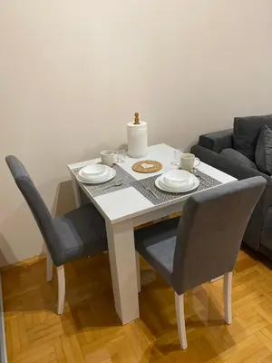 a dining room table with two chairs and a white table with plates at Apartman Breza 3 in Kruševac