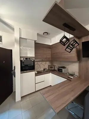 a kitchen with white cabinets and a wooden counter top at Matic Apartmani 4 in Trnava