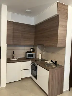 a kitchen with white and wooden cabinets and a sink at Matic Apartmani 4 in Trnava