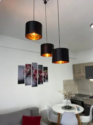 a kitchen with three lights hanging over a table at R Lux Apartman Jagodina Akva Park in Jagodina