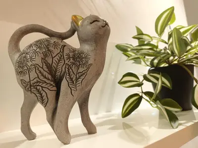 a figurine of a cat with flowers on its back next to plants at Apartman Damjan Sokobanja in Soko Banja