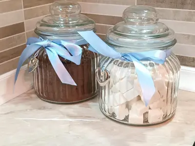 two glass jars with blue bows on top of a counter at Apartman Damjan Sokobanja in Soko Banja