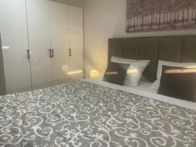 a bedroom with a large bed with a black and white blanket at luxury Pool Apartment Jagodina in Jagodina