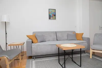 a living room with a gray couch and two chairs at City Center Condo Vranje in Vranje