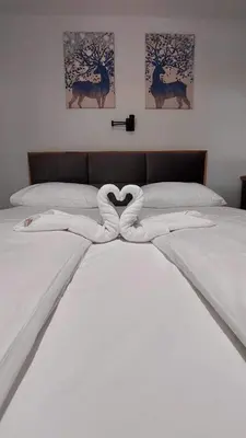 two beds with white sheets with a heart shapedvisor at Apartman Mist - Bela Reka Kopaonik in Brzeće