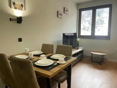 a dining room with a table and chairs and a television at Apartman Mist - Bela Reka Kopaonik in Brzeće