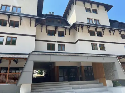 a large white building with a roof at Apartman Mist - Bela Reka Kopaonik in Brzeće