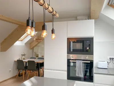 a kitchen with white cabinets and a table with chairs at Agro Lux Apartment - Milenović in Soko Banja